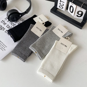 Detailed macro view of four solid color ribbed mid-calf cotton socks in minimalist layout