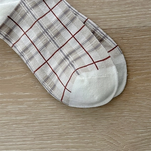 Detail of plaid knit socks showing the white toe cap and red and brown checkered pattern