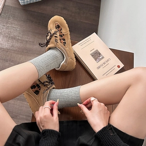 Gros plan de baskets léopard kaki avec chaussettes côtelées grises sur bois sombre
