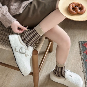 Detail of brown plaid mid-calf socks with white plush buckled clogs in cozy autumn style