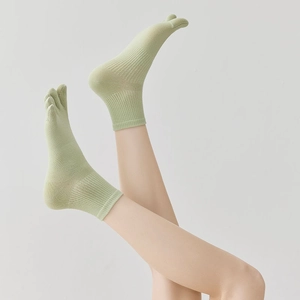 Detail of light green five-finger socks showing toe separation and ribbed texture