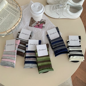 Flat lay of colorful striped cotton socks with minimalist branding on a table