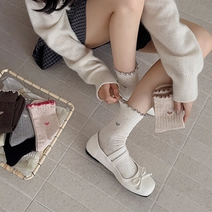 Détail de la broderie cœur et bords ondulés sur chaussettes à pois colorées