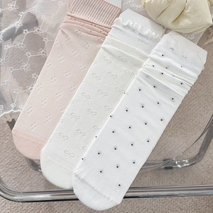 Details von drei beigen Schleifensocken mit Blumen- und Punktmustern auf Spitze