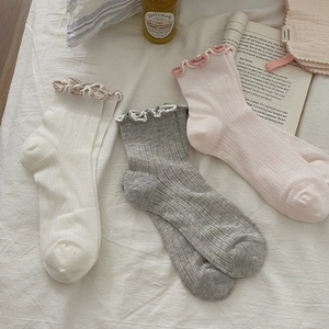 Detail of three-pack cotton socks in cream, grey, and pink with lettuce trim edge