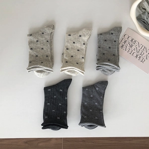 Close-up of five pairs of ribbed knit socks in grey tones with delicate bow accents