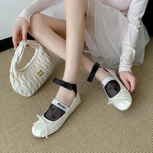 Close-up of elegant white ballet flats with black ribbon ties and quilted handbag