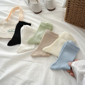 Flat lay of colorful breathable cotton crew socks in diverse pastel tones on white cloth