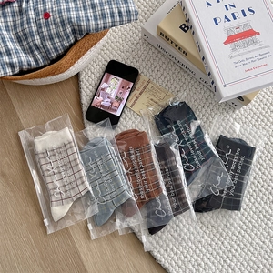 Detail view of British style plaid crew socks in diverse colors with zip bag packaging