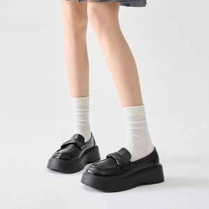 Detail of black platform loafers paired with white mid-calf socks in college style