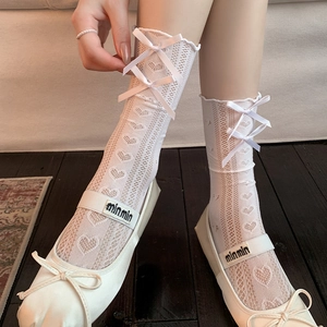 Close-up of white lace mid-calf socks with heart cutouts and bow details on Mary Janes