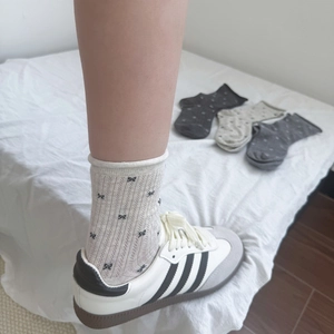Detail of ribbed cotton socks with bow patterns and rolled cuffs in various shades of grey