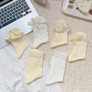 Close-up of ballet-style cream yellow socks with delicate lace trim and ribbon bows