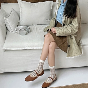 Detail of vintage plaid mid-calf socks paired with brown Mary Jane shoes and a pleated skirt