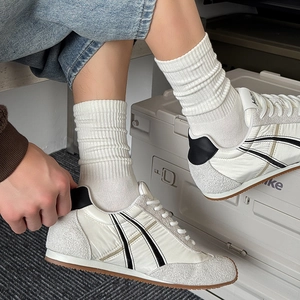 Detail of white low-top sneakers with grey suede panels and high-top cotton socks