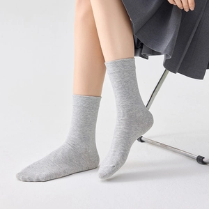 Detail of light gray cotton knit mid-calf socks with ribbed cuffs on female model