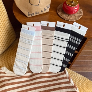 Set of five striped cotton crew socks in pastel and neutral tones on a wooden surface