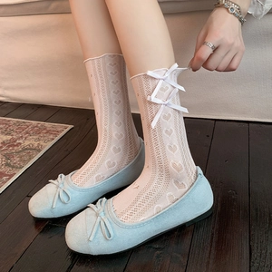 Detail of white lace heart socks with ribbon bow paired with light blue ballet flat shoes