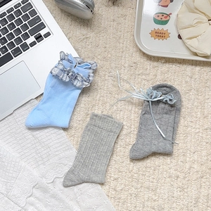 Détail des chaussettes à carreaux bleus et chaussettes grises avec nœuds en ruban