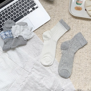 Détail de chaussettes japonaises en coton avec bordure en dentelle et motifs rayés sur tapis