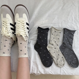 Detail of grey bow pattern socks with rib texture and rolled edges on soft fabric