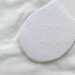 Close-up of breathable white mesh knit fabric and intricate lace texture on ballet socks