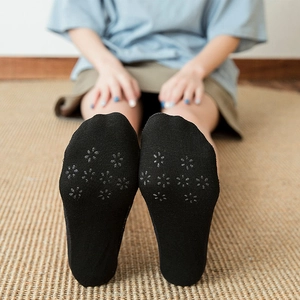 Close-up of black low cut socks featuring floral non-slip silicone grippers on the sole