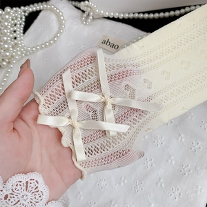 Detail of cream white lace mesh socks featuring delicate bow accents and lettuce edge trim