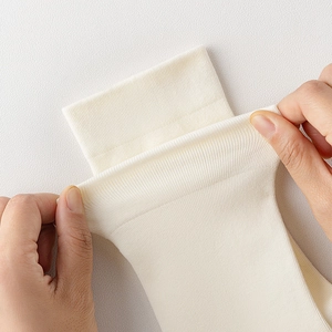Detailed close-up showing high-elasticity ribbed cuff of cream white mid-calf socks