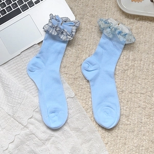 Chaussettes bleues à carreaux avec volants et nœuds dans un décor doux et minimaliste