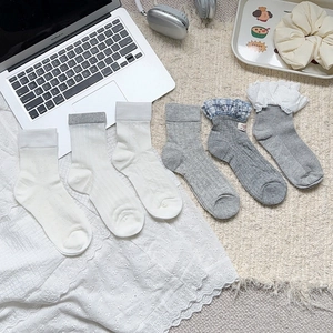 Lot de chaussettes style japonais avec dentelle en blanc et gris sur fond de tapis doux