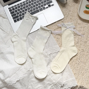 Close-up of lolita lace socks with satin bows and intricate mesh knit texture