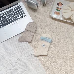 Detail of preppy cotton crew socks featuring cute blue bow embroidery and ribbed texture