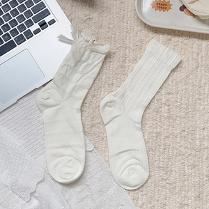 Detail of white cotton bow socks with ruffled edges shown in a cozy aesthetic setting
