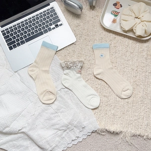 Three pairs of preppy style crew socks with lace trim and heart embroidery in cream colors