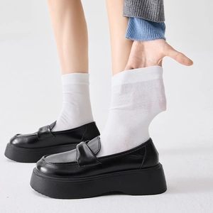 Detail shot showing the elasticity and thin fabric of white calf-length cotton socks