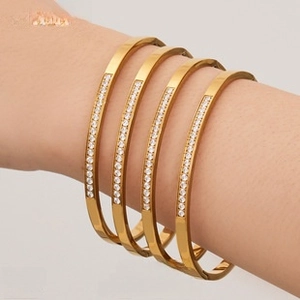 Close-up of four gold-plated stainless steel bangles set with crystals on a wrist