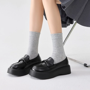 Classic black platform loafers styled with grey socks for a preppy college fashion look