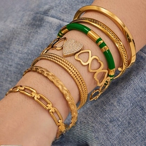 Close-up of stacked 18k gold plated bracelets with enamel and rhinestone details