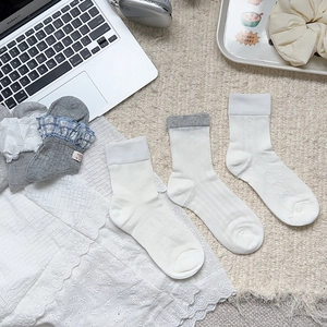 Détail de chaussettes en coton avec bordures en dentelle et revers côtelés en blanc et gris