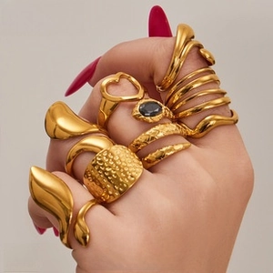 Close-up of assorted gold rings with heart, snake, and gemstone designs on model's fingers