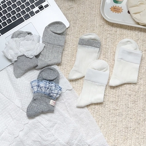 Vue détaillée de chaussettes blanches et grises avec dentelle et motifs à carreaux bleus