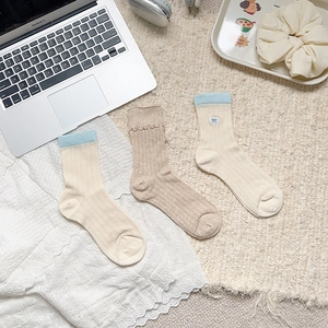 Three pairs of preppy style crew socks with ribbon bow embroidery in cream and khaki colors