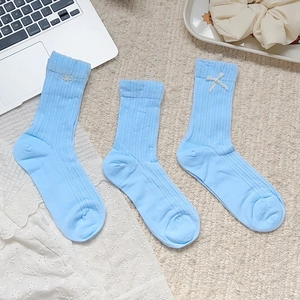 Détail de chaussettes en coton bleu clair avec nœuds en dentelle blanche et maille côtelée