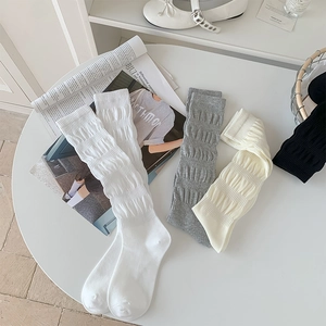 Detailed view of ribbed cotton slouch socks in white grey and beige tones