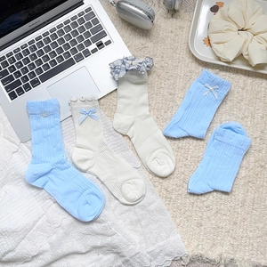 Chaussettes style preppy bleues et blanches avec dentelle et nœuds sur un tapis