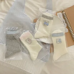 Détail de broderie d'ours et texture maille respirante sur chaussettes en coton crème
