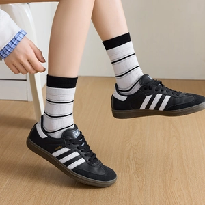 Close-up of sporty striped crew socks paired with classic black leather sneakers