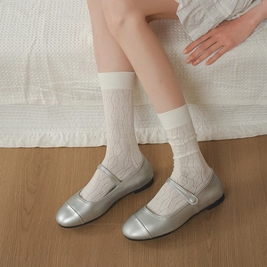 Dettaglio di calze bianche in cotone a rombi abbinate a scarpe Mary Jane argento