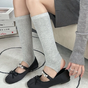 Detail of grey ribbed knit stirrup leg warmers paired with ballet flats for a trendy look
